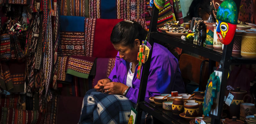 Woman sewing a blanket in cusco