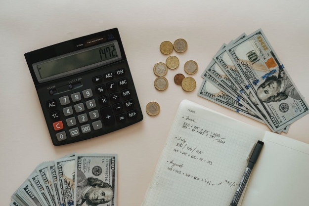 dinero, calculadora y libreta con cálculos sobre el cambio de divisas