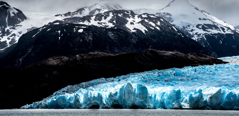 grey glacier with snowy mountain in patagonia