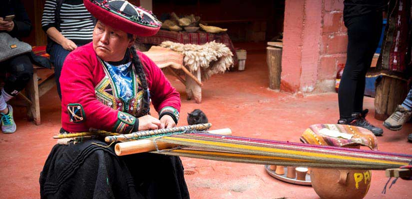 mujer en mercado de peru tejiendo ropas tradicionales