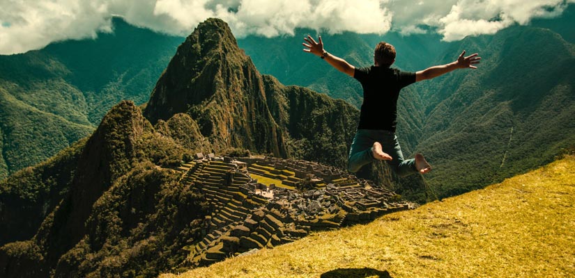 man jumping in machu picchu with views to huayna picchu