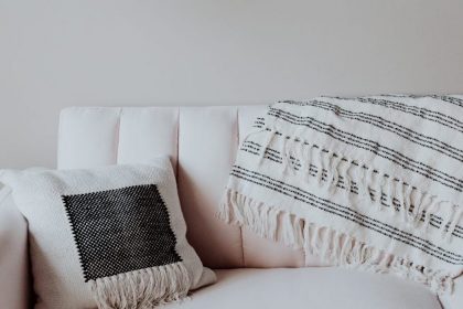 White couch with cushion and blanket