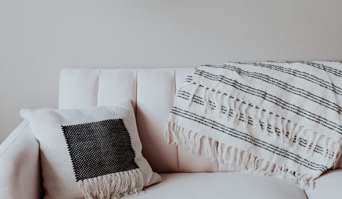 White couch with cushion and blanket