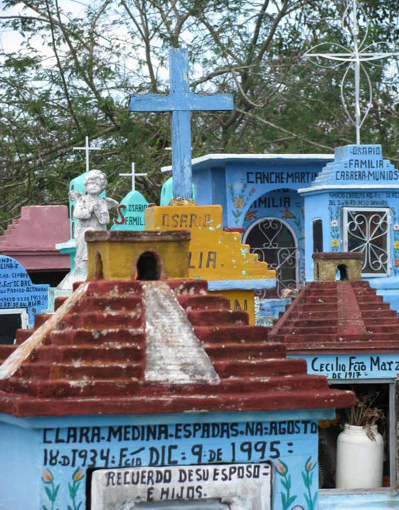Tumbas coloridas con formas de casas maya y cruces católicas