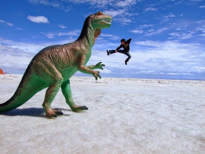man playing with perspective on a toy dinoasaurus
