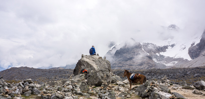 person seat in a rock and a mule in the salkantay trekking