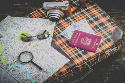 un mapa, dinero, cámara y gafas de sol encima de una maleta